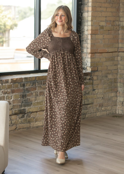Brown floral maxi dress in a lifestyle setting, showing the square neckline, lace bodice, and long sleeves.