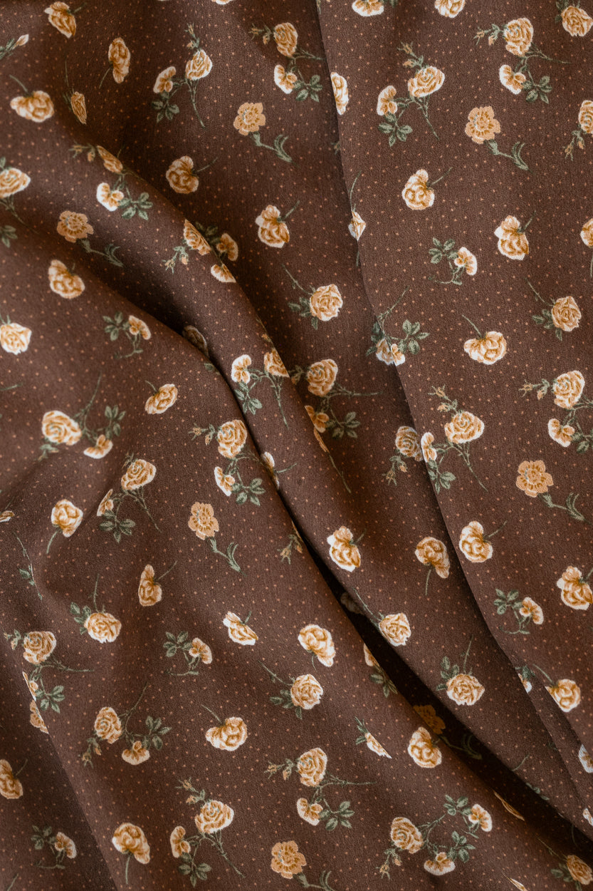 Close-up of the Elise dress fabric showing cream rose florals with muted green leaves on a brown background.