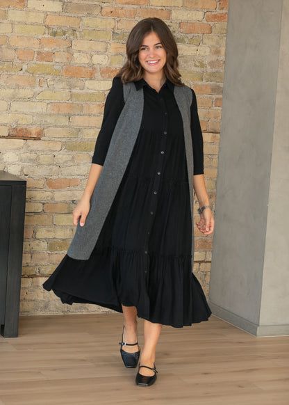Black Elsie midi dress with half sleeves, button front, and tiered A-line skirt, styled indoors.
