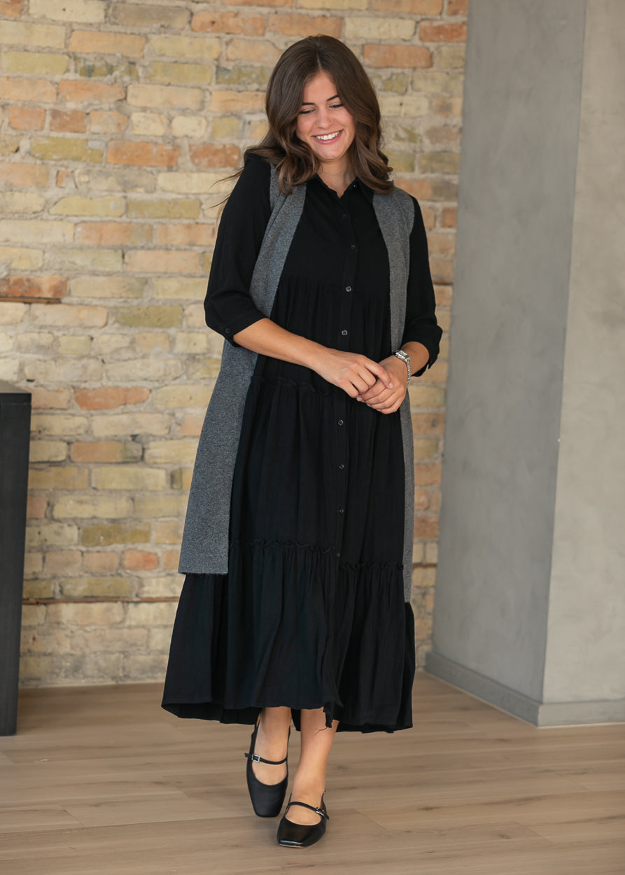 Black button front midi dress styled on model with a tiered calf-length skirt.