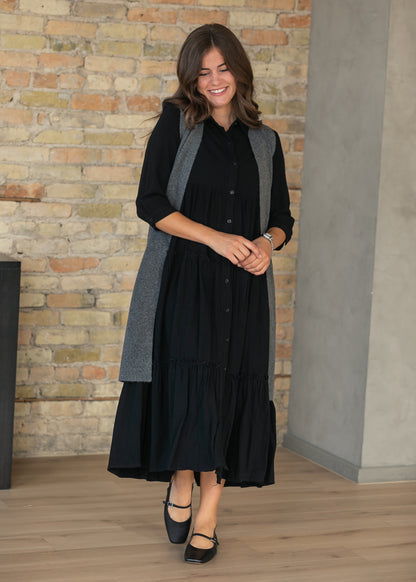 Black button front midi dress styled on model with a tiered calf-length skirt.