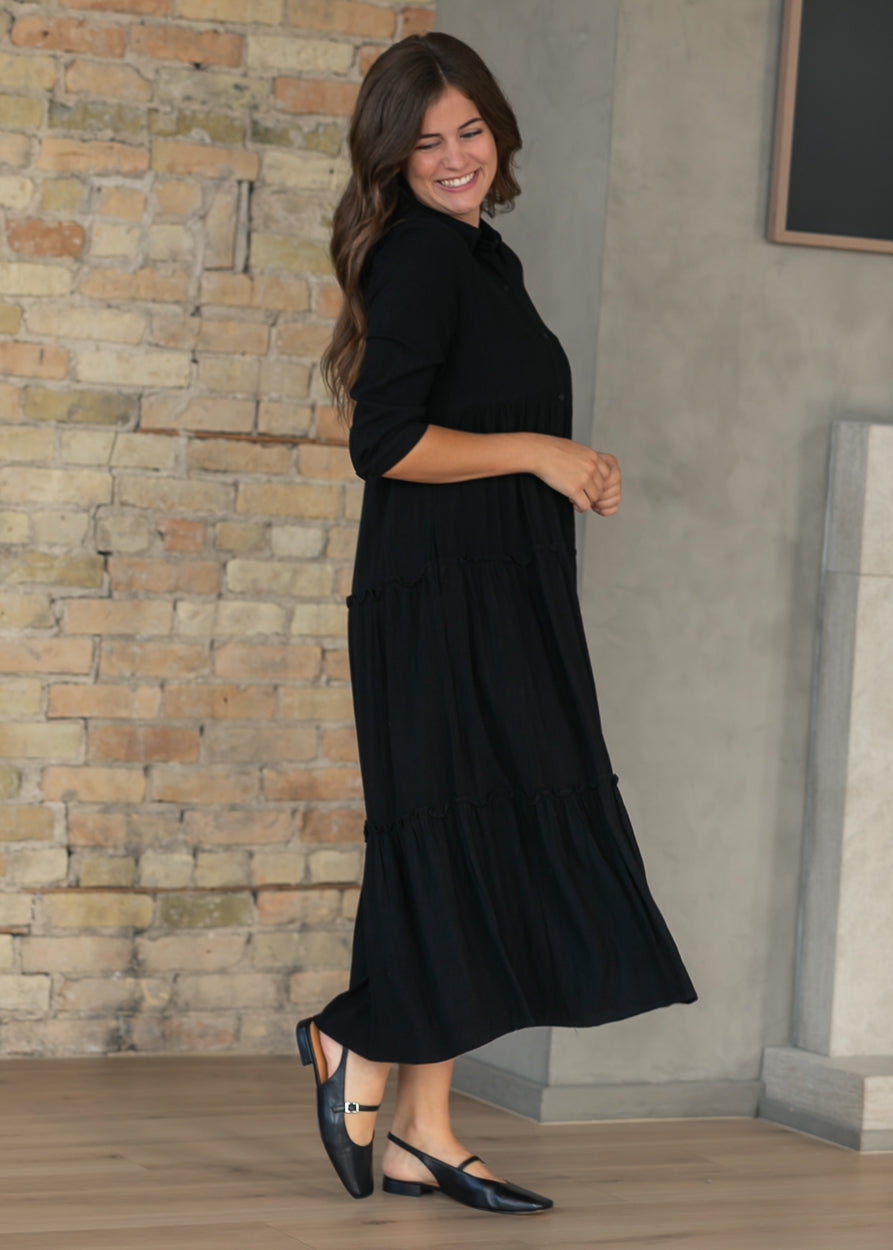 Side of black Elsie midi dress showing the V-neck, button front, and A-line shape.