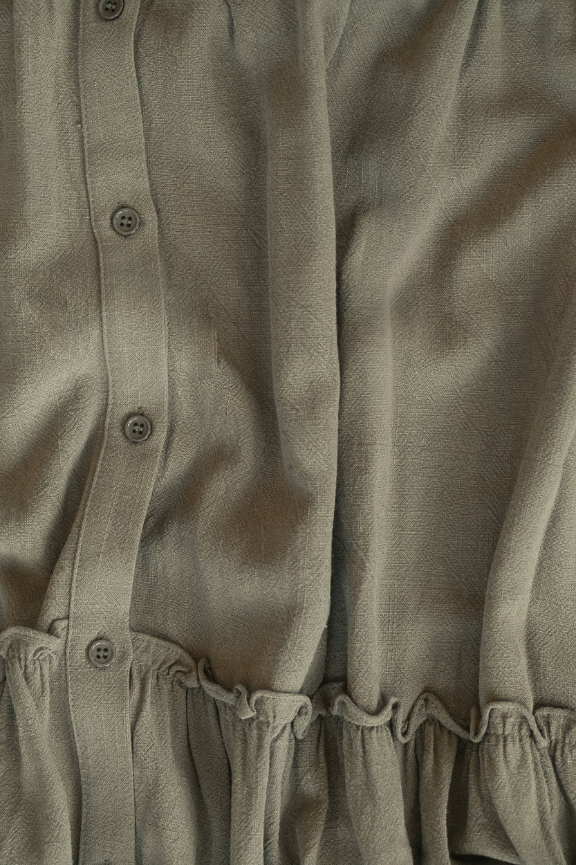Close-up of olive Elsie dress showing the functional button front and gathered tier detail.