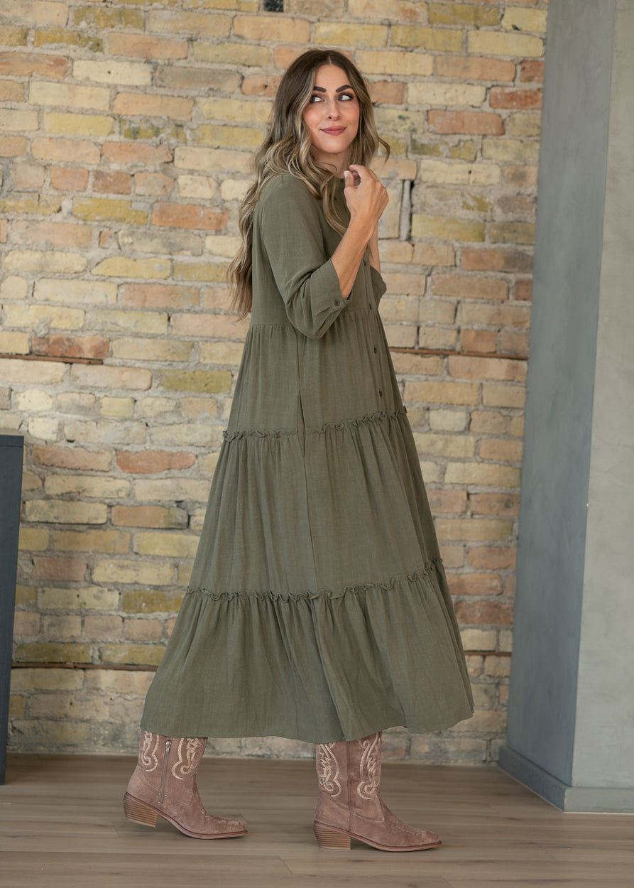 Side view of olive midi dress showing the tiered A-line silhouette and half sleeves.