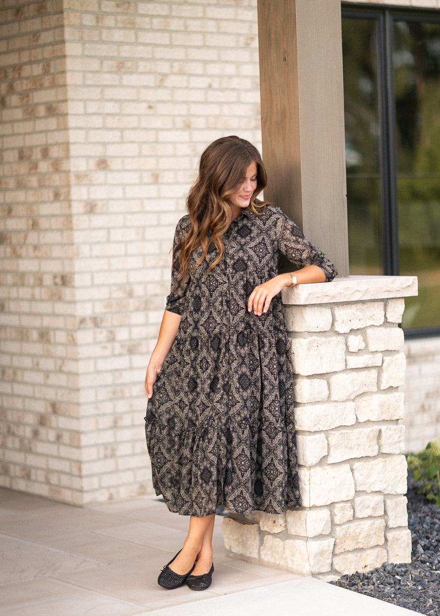 Black and cream paisley midi dress styled beside a stone ledge.