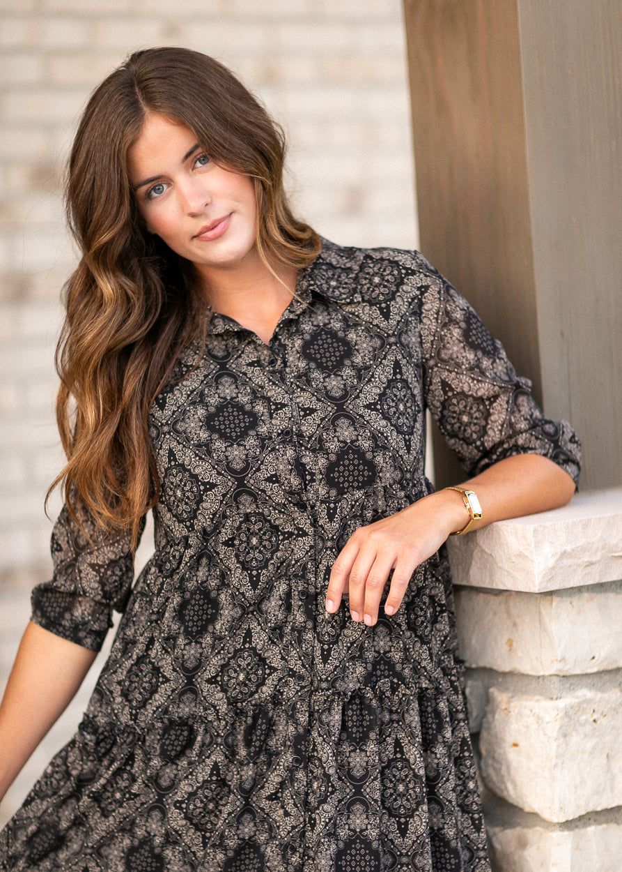 Close-up of black and cream paisley dress showing the V-neck and button front.