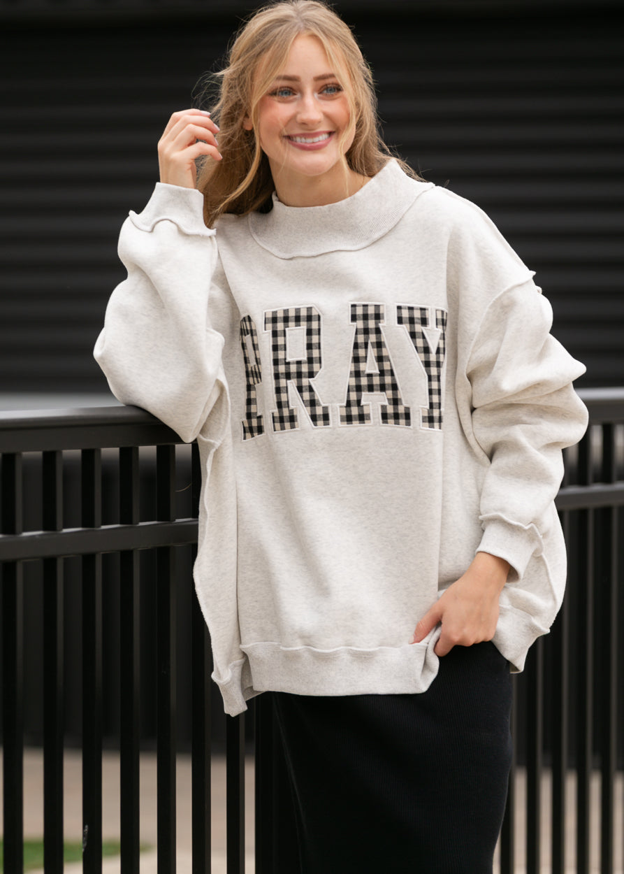 Front view of oatmeal sweatshirt with gingham Pray lettering, mockneck, and relaxed sleeves.