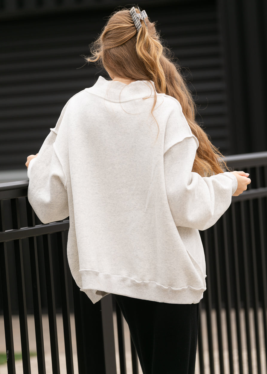 Back of oatmeal heather mockneck sweatshirt showing oversized fit, dropped shoulders, and ribbed hem.