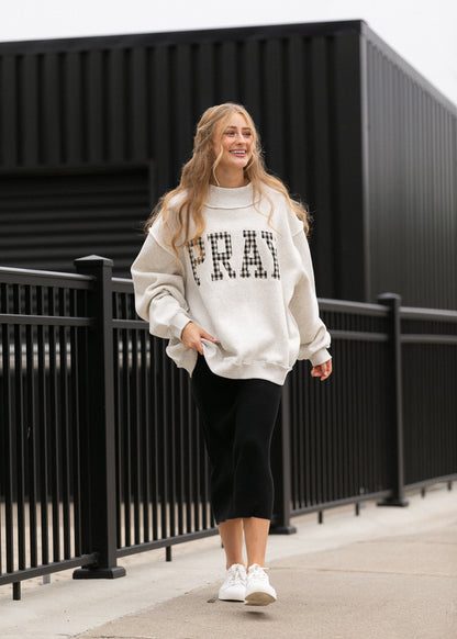 Oatmeal Pray mockneck sweatshirt styled with a black midi skirt and white sneakers.