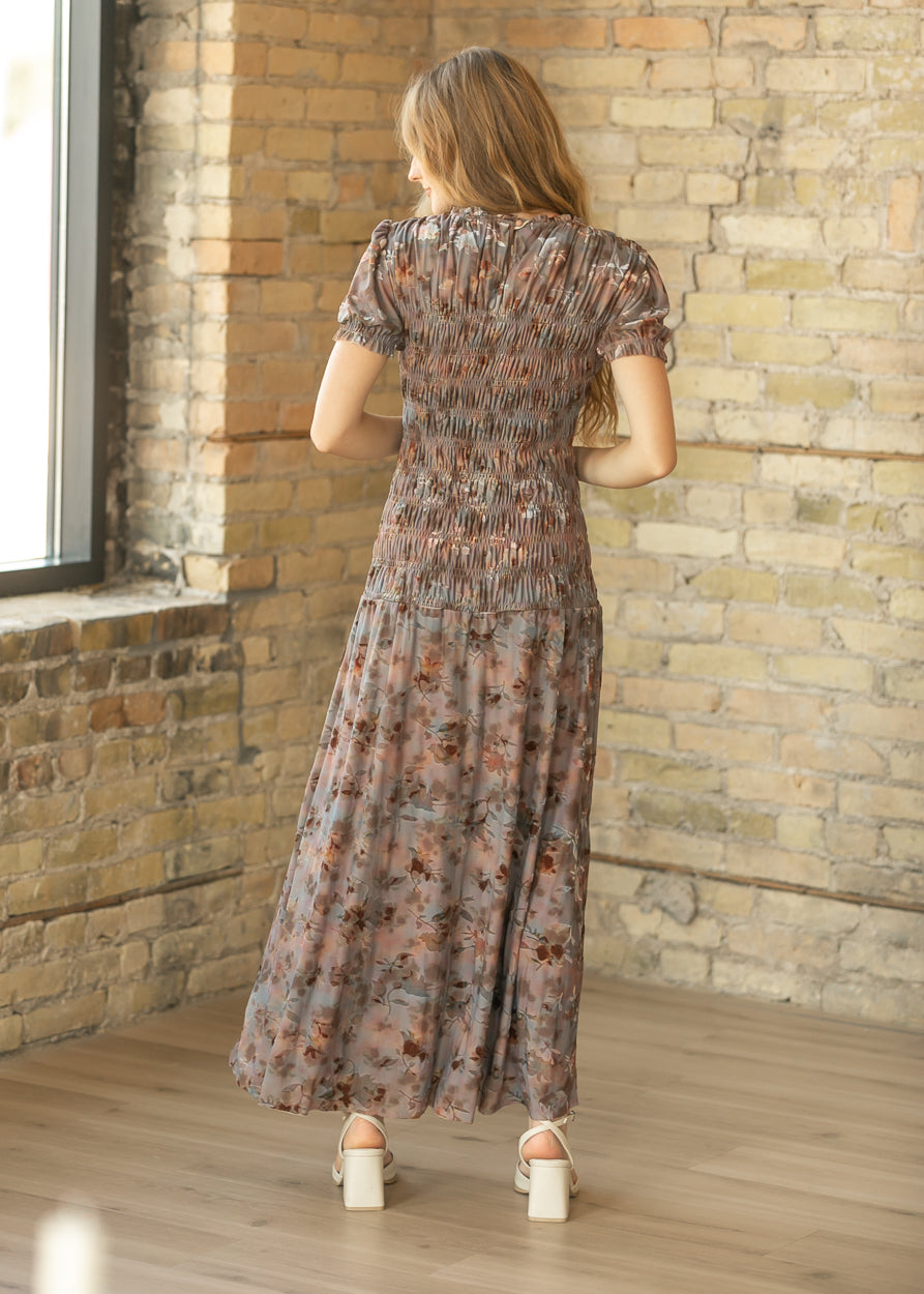 Back of floral smocked maxi dress showing stretchy smocking, short puff sleeves, and ankle-length skirt.