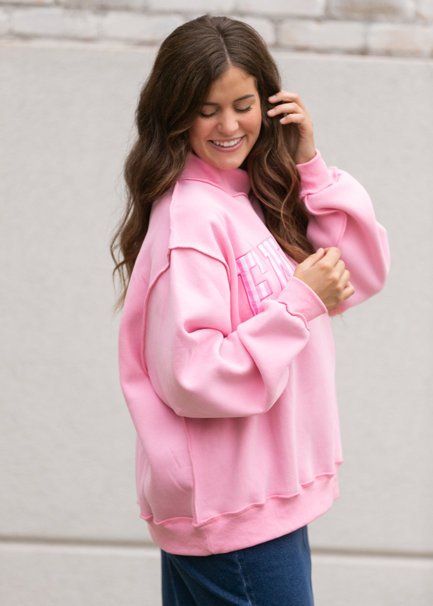 Pink Faith mockneck sweatshirt styled with a dark wash denim midi skirt and white shoes.