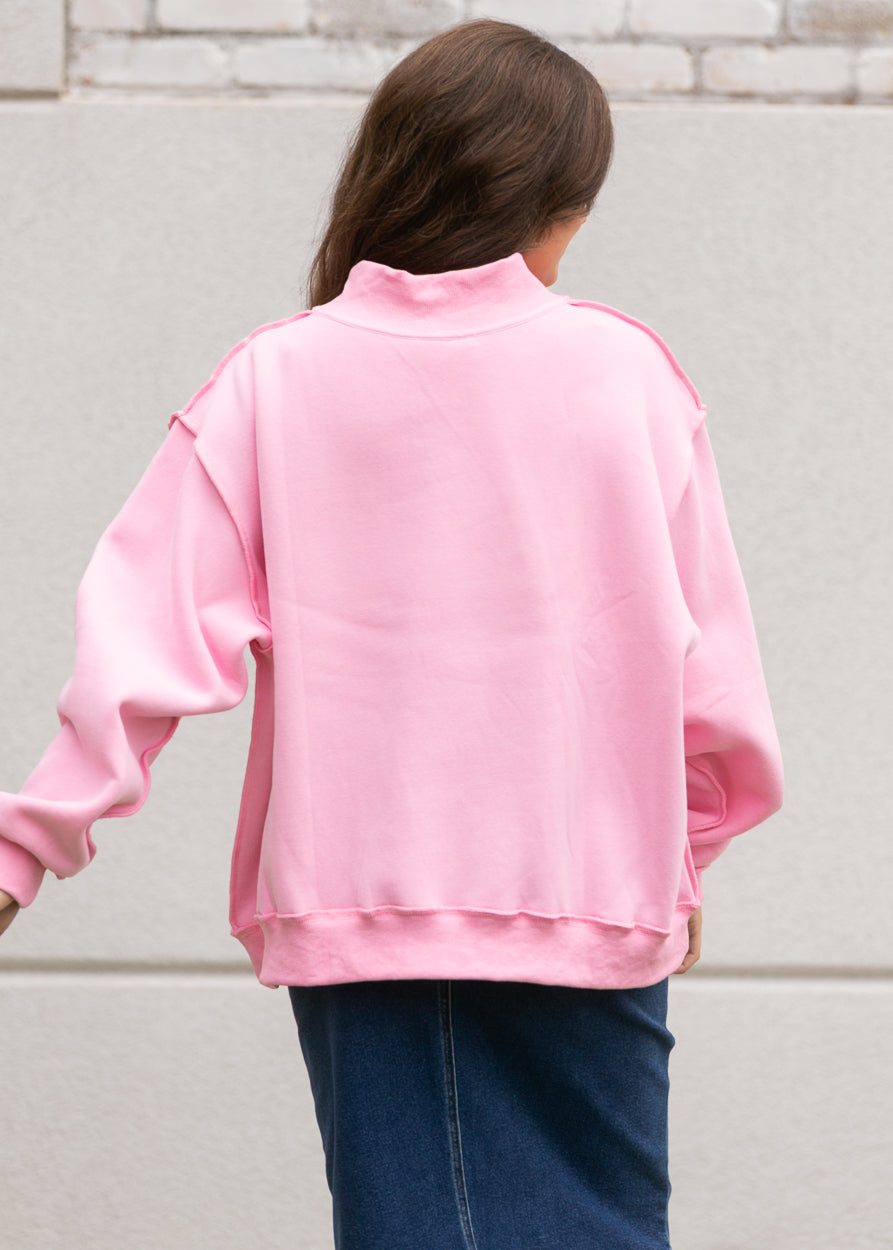 Back of bright pink oversized mockneck sweatshirt showing dropped shoulders and relaxed fit.