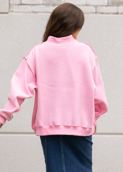 Back of bright pink oversized mockneck sweatshirt showing dropped shoulders and relaxed fit.