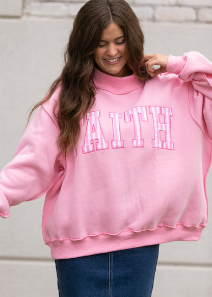 Pink mockneck sweatshirt with pink-and-white gingham Faith lettering and oversized silhouette.
