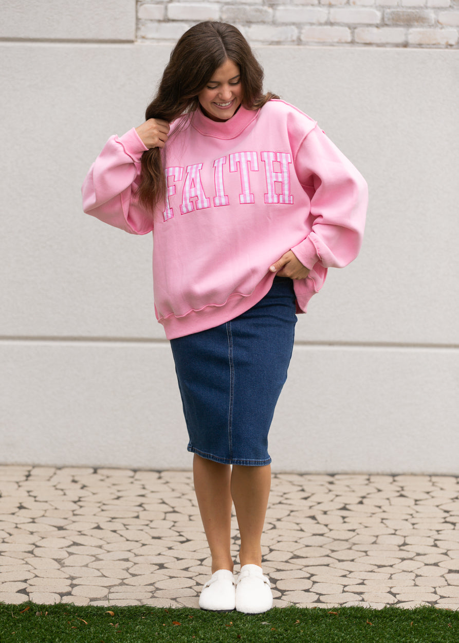 bright pink mockneck sweatshirt showing gingham Faith lettering and ribbed neckline.