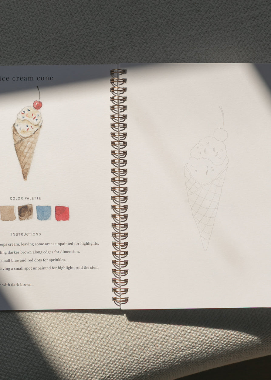 Step-by-step watercolor workbook spread featuring ice cream cone painting instructions and sketch outline.