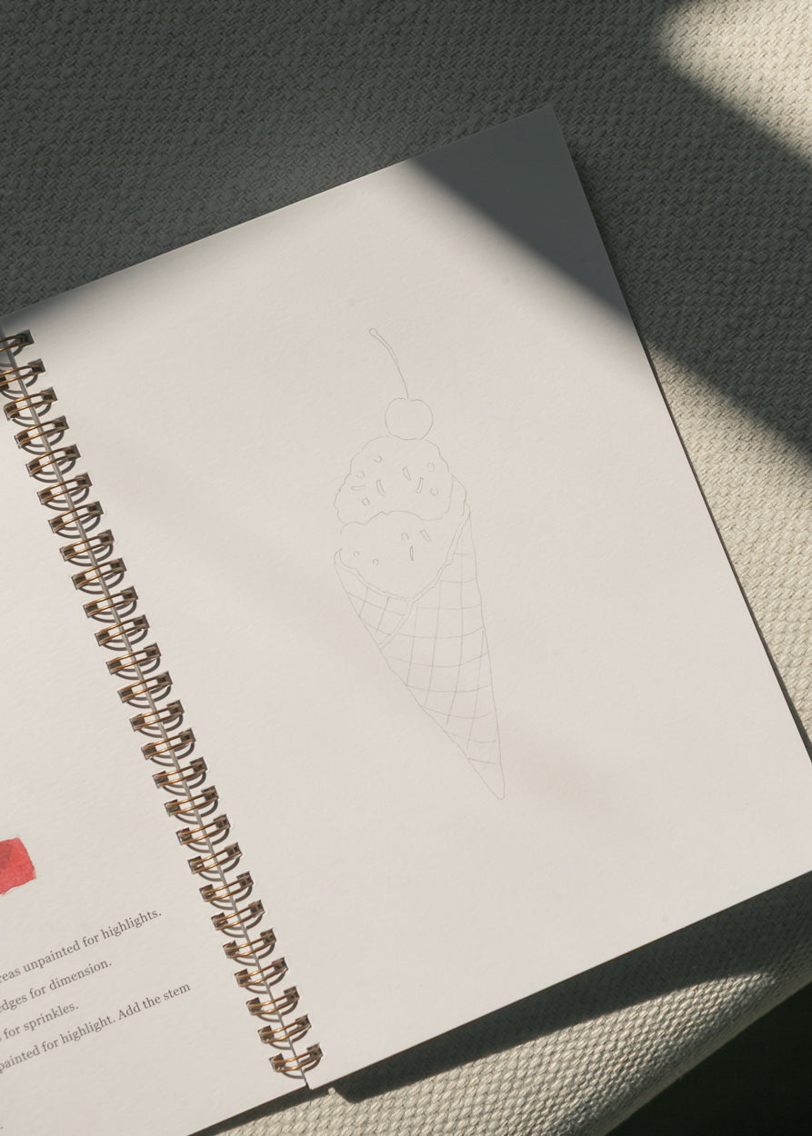 Americana watercolor workbook open to an ice cream cone sketch practice page.