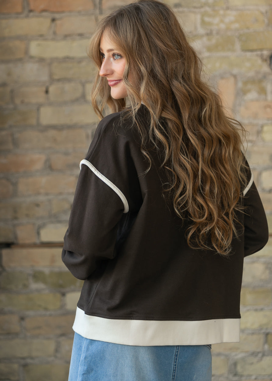 Back of espresso crewneck sweater showing drop shoulders and cream contrast hem and sleeve trim.