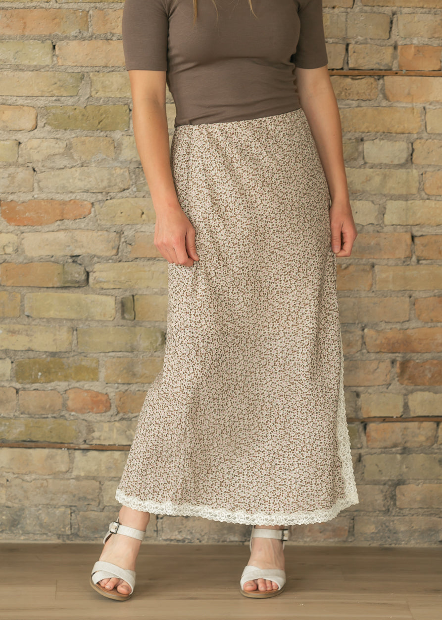 Floral lace hem midi skirt with side slit and flowing silhouette, styled with neutral heels.