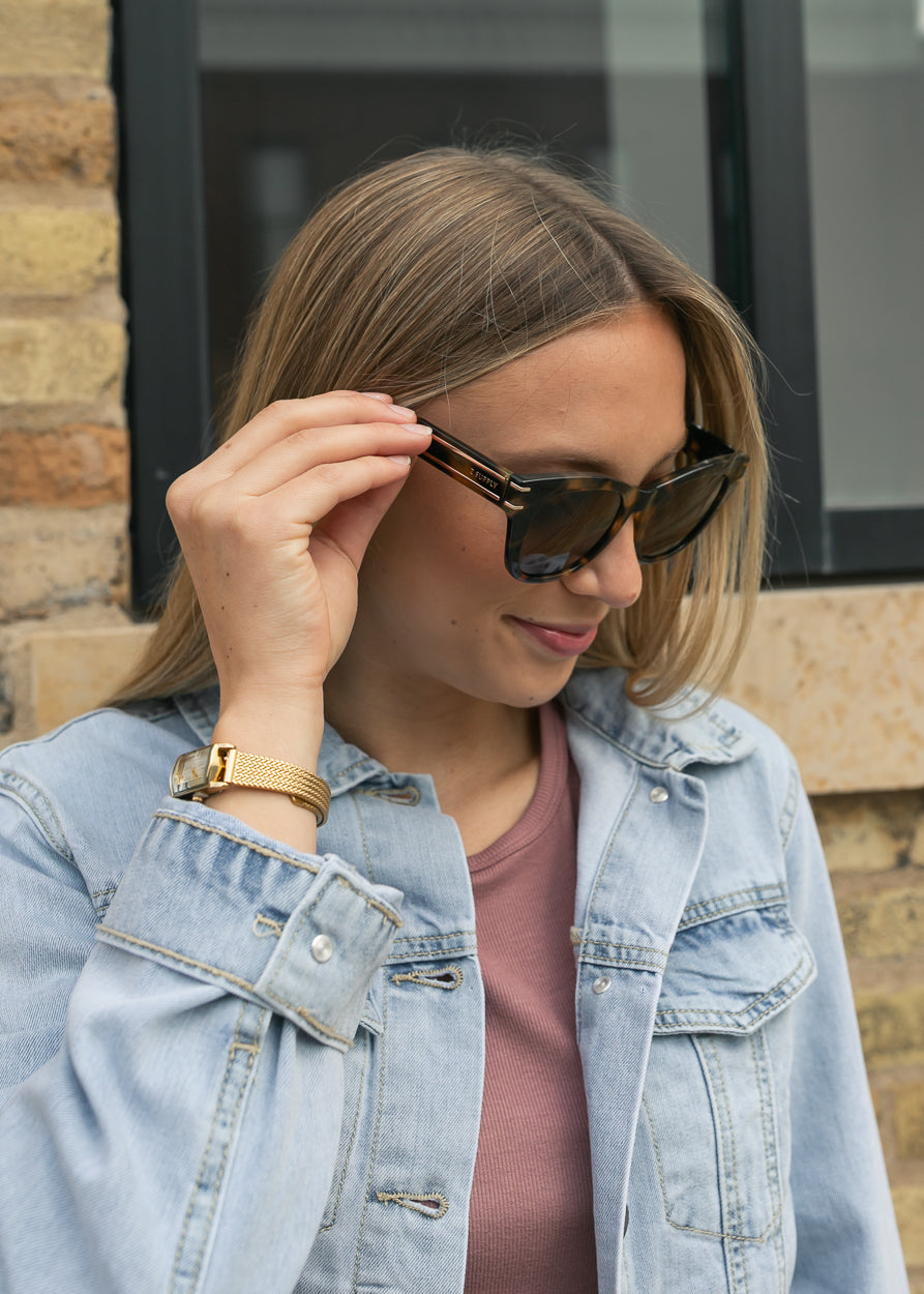Tortoise polarized sunglasses with medium square frame styled with a light wash denim jacket.
