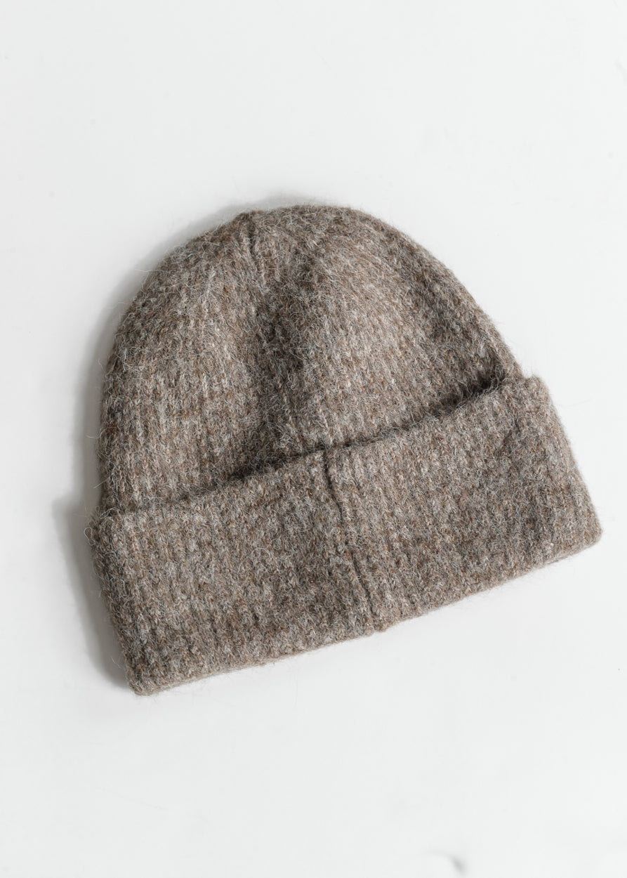 Taupe fuzzy ribbed beanie laid flat, showing its simple cold-weather silhouette.