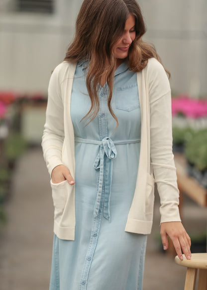 Woman wearing a light blue dress with a cream cardigan in an outdoor setting