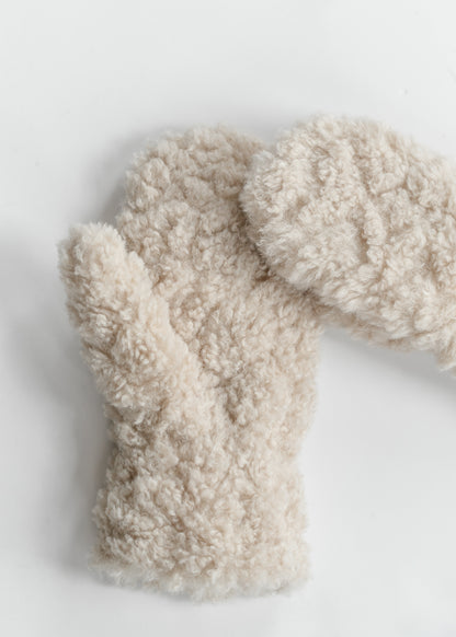 Close-up of beige faux shearling mitten showing the plush curly polyester texture.