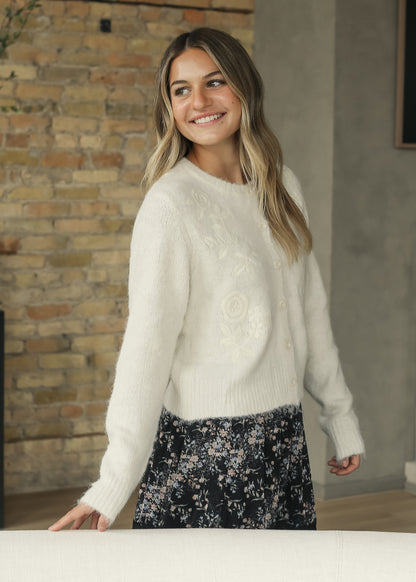 Ivory floral embroidered cardigan with ribbed trim, styled as a soft feminine layer.