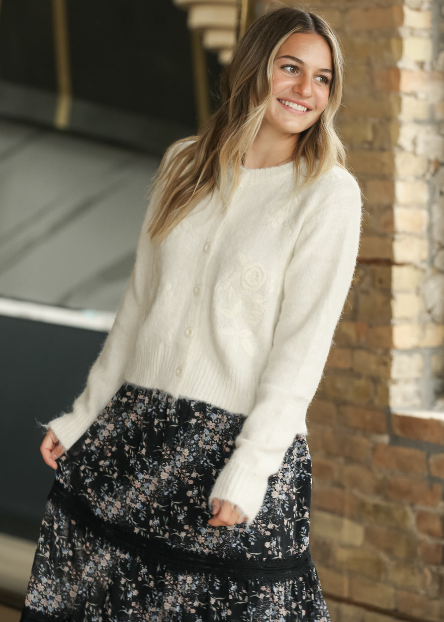Semi-fitted ivory knit cardigan with functional button front and tonal floral embroidery.
