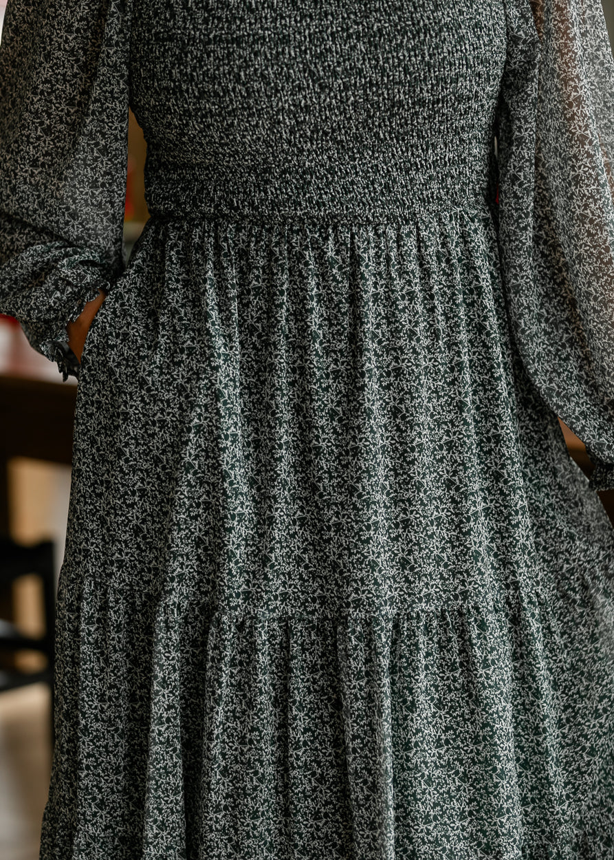 Close-up of hunter green floral midi dress showing the tiered skirt, side pocket, and petite ivory print.