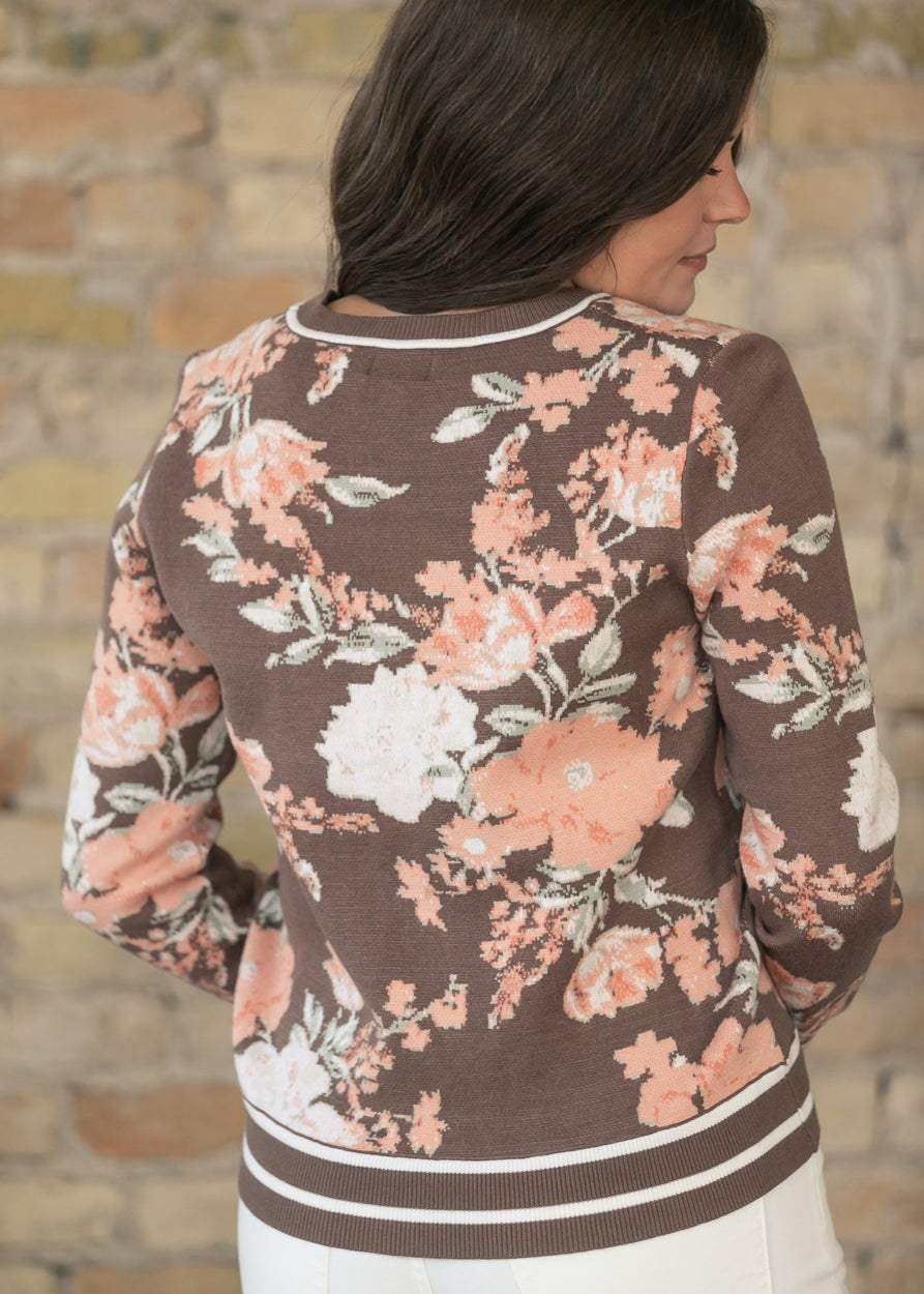 Back of brown floral jacquard sweater showing peach and cream floral pattern and striped hem trim.