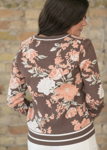 Back of brown floral jacquard sweater showing peach and cream floral pattern and striped hem trim.