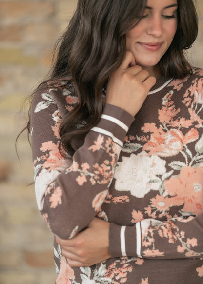 Close-up of brown floral jacquard sweater showing peach florals and striped cuff detail.