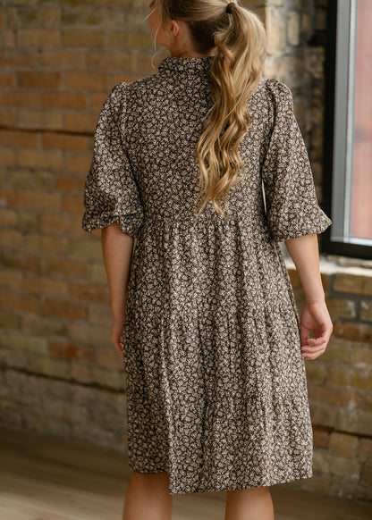 Back of brown floral button-up dress showing gathered waist, puff sleeves, and knee-length hem.