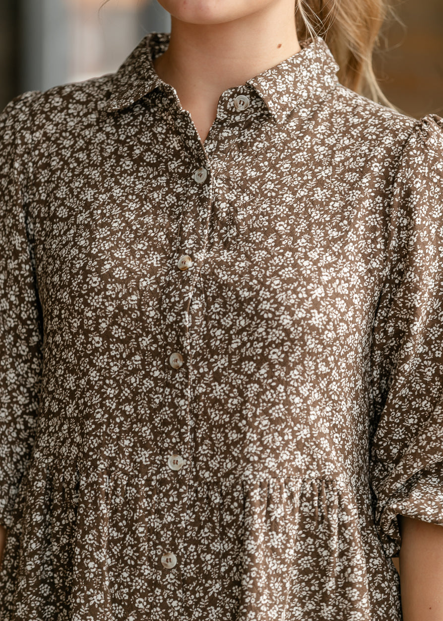 Close-up of collared neckline and petite cream floral print on brown fabric.