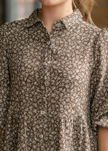 Close-up of collared neckline and petite cream floral print on brown fabric.