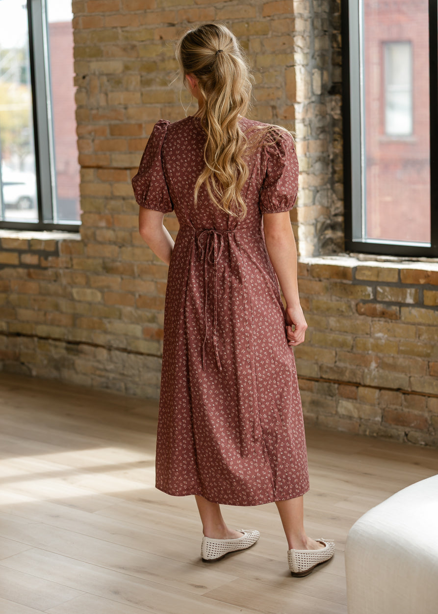 Back of brown floral midi dress showing petite cream print, puff sleeves, and tie waist.