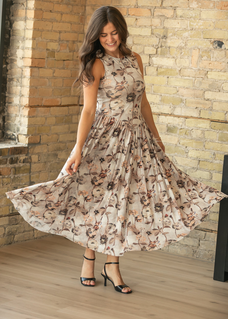 Front view of neutral floral maxi dress in motion, showing the full gathered skirt and fitted bodice.