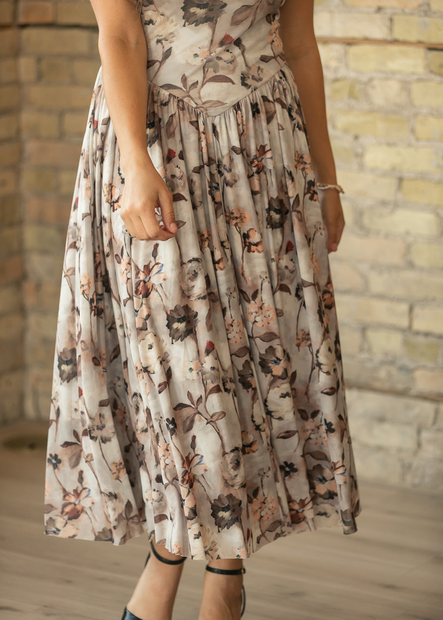 Close-up of neutral floral maxi dress showing the pointed waist seam and gathered skirt.