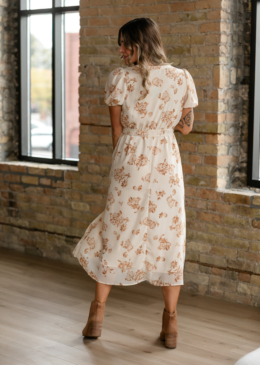 Back of cream floral midi dress showing taupe print, puff sleeves, and flowing midi skirt.
