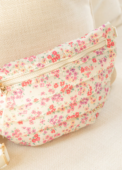 Floral quilted belt bag with adjustable strap displayed on a cream chair.