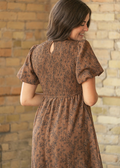 Back of brown floral midi dress showing full smocked bodice, short puff sleeves, and keyhole detail.