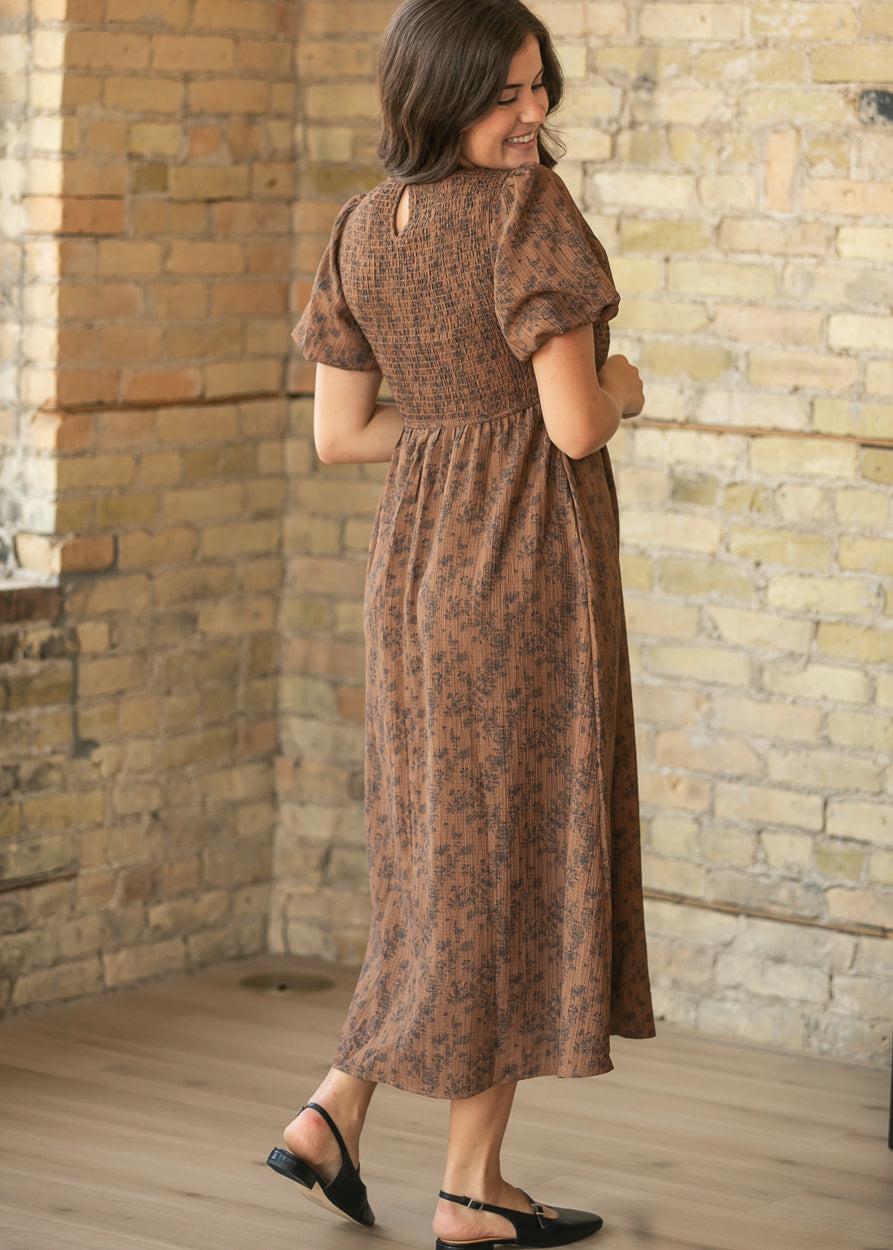 Full back view of brown floral midi dress with smocked bodice and softly gathered skirt.