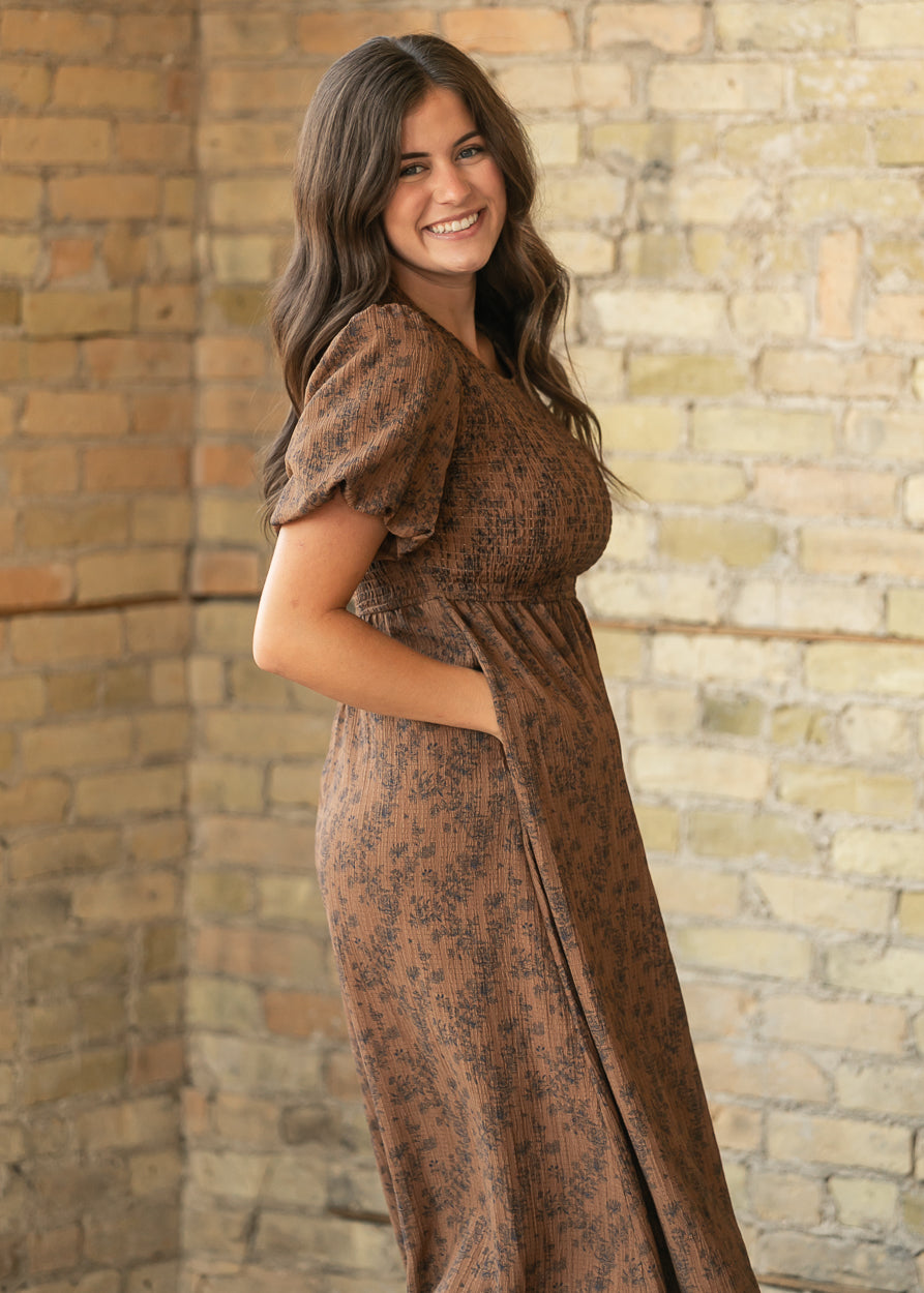 Brown floral midi dress from the side showing smocked bodice, puff sleeves, and side pocket.
