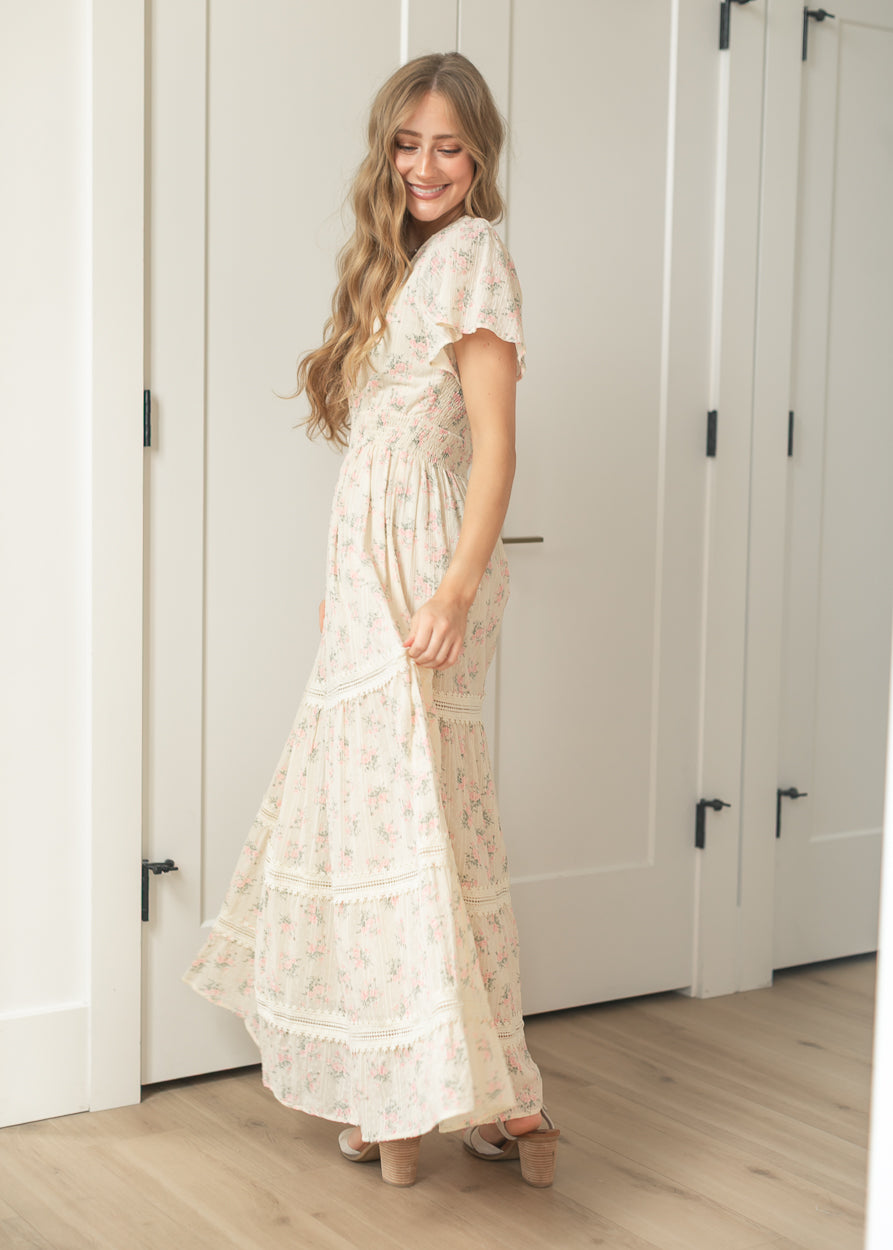 Feminine ivory floral dress featuring flutter sleeves and ruffle hem