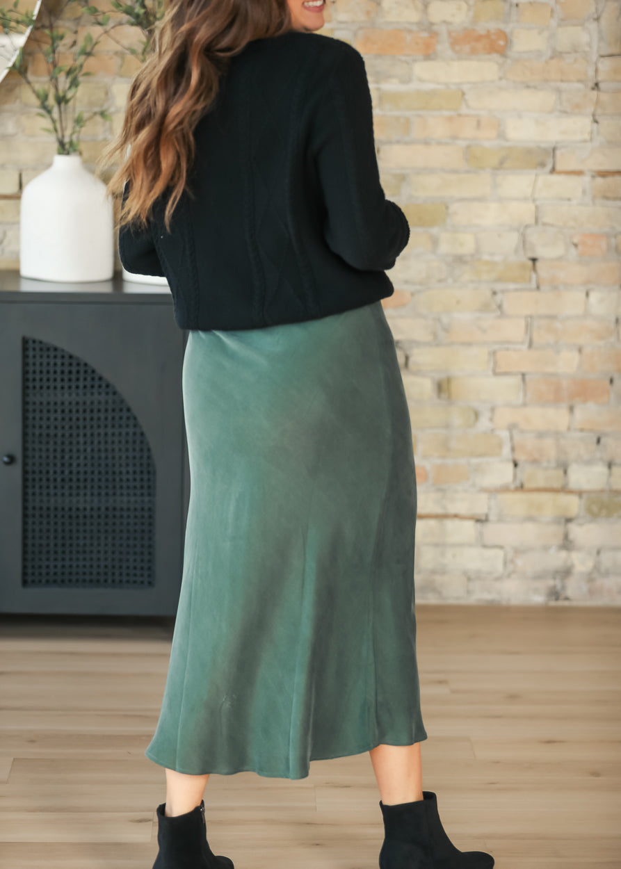 Back view of emerald faux suede midi skirt styled with a black sweater