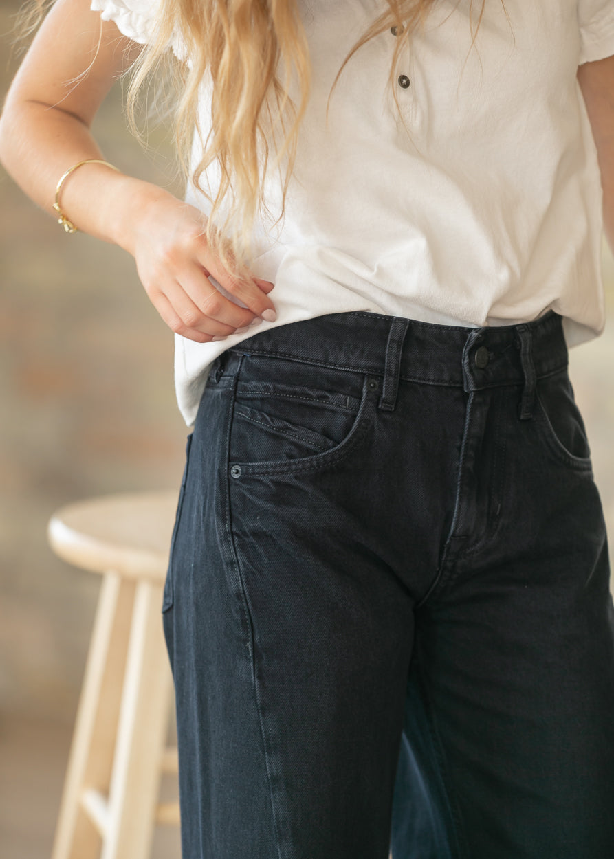 Close-up of black denim boyfriend jeans showing high rise waistband and front pocket detail