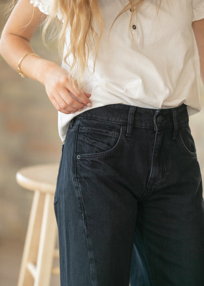 Close-up of black denim boyfriend jeans showing high rise waistband and front pocket detail