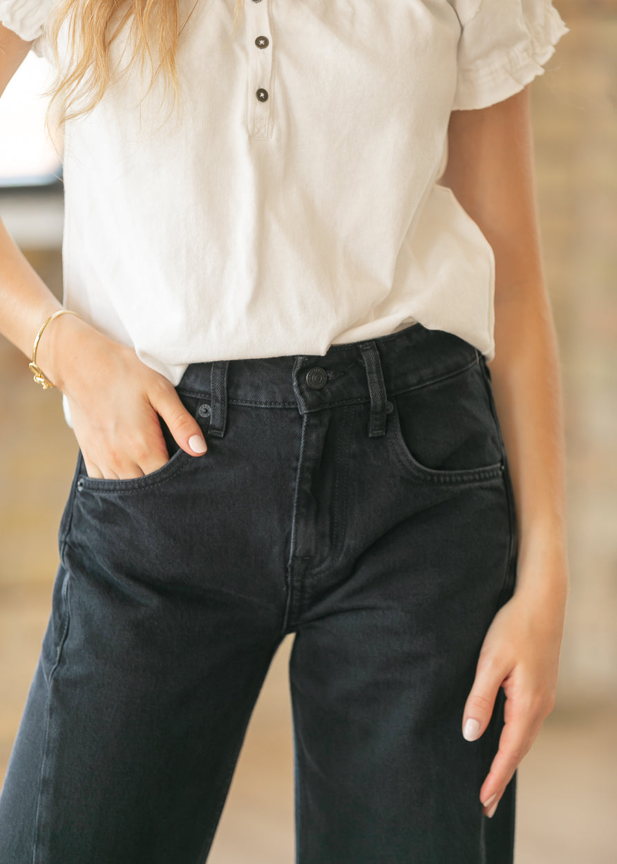 Close-up of black denim boyfriend jeans showing high rise waistband and front pocket detail