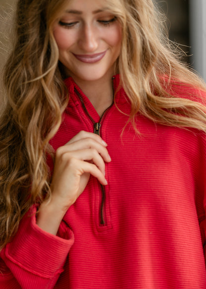 Close-up of red ribbed cotton top showing quarter-zip neckline and textured fabric.